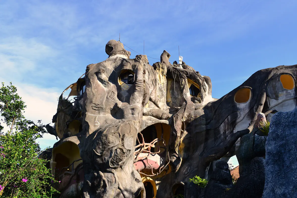 The giant tree-trunk block of the Crazy House in Da Lat, with round windows, under a blue sky