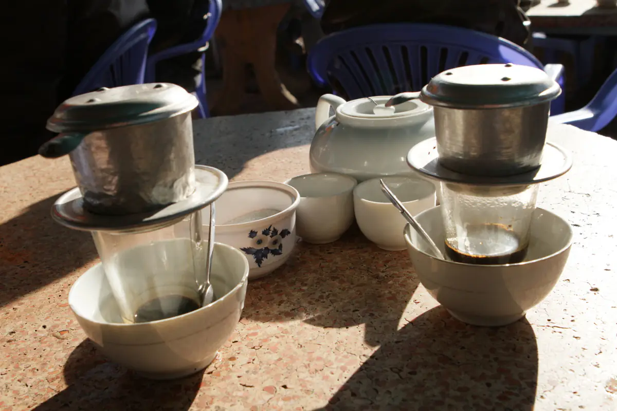 Hai phin cà phê nhỏ giọt đặt trên cốc trong bát nước nóng, kèm ấm trà tại một quán cà phê ở Đà Lạt