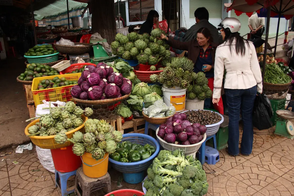 Sạp rau củ, atiso và bông cải ở chợ Đà Lạt, nơi du khách mua đặc sản và tính chi phí du lịch Đà Lạt