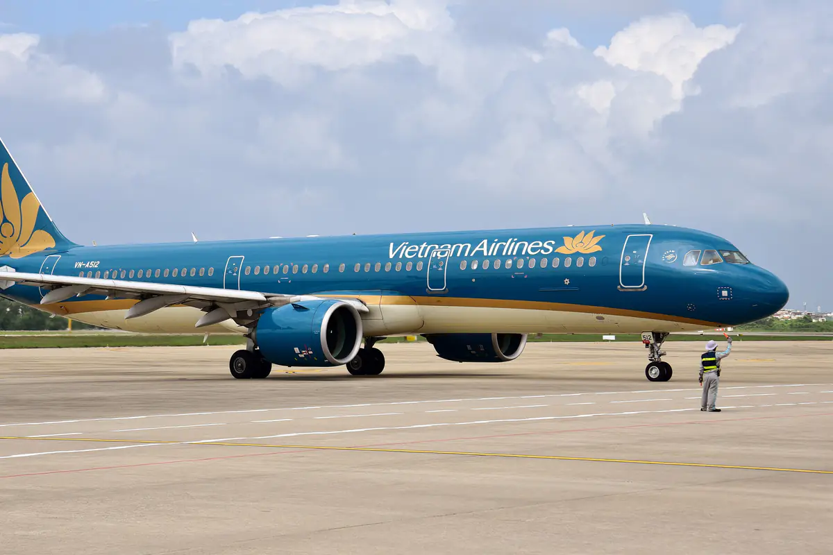 A Vietnam Airlines Airbus A321neo taxiing toward the domestic terminal at Da Nang International Airport, guided by ground crew