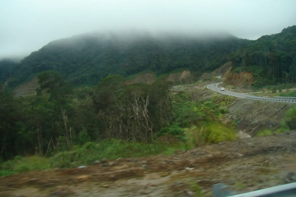 A winding mountain stretch of the old Road 723, now part of National Route 27C between Da Lat and Nha Trang, with cloud on the ridge and bare cut slopes