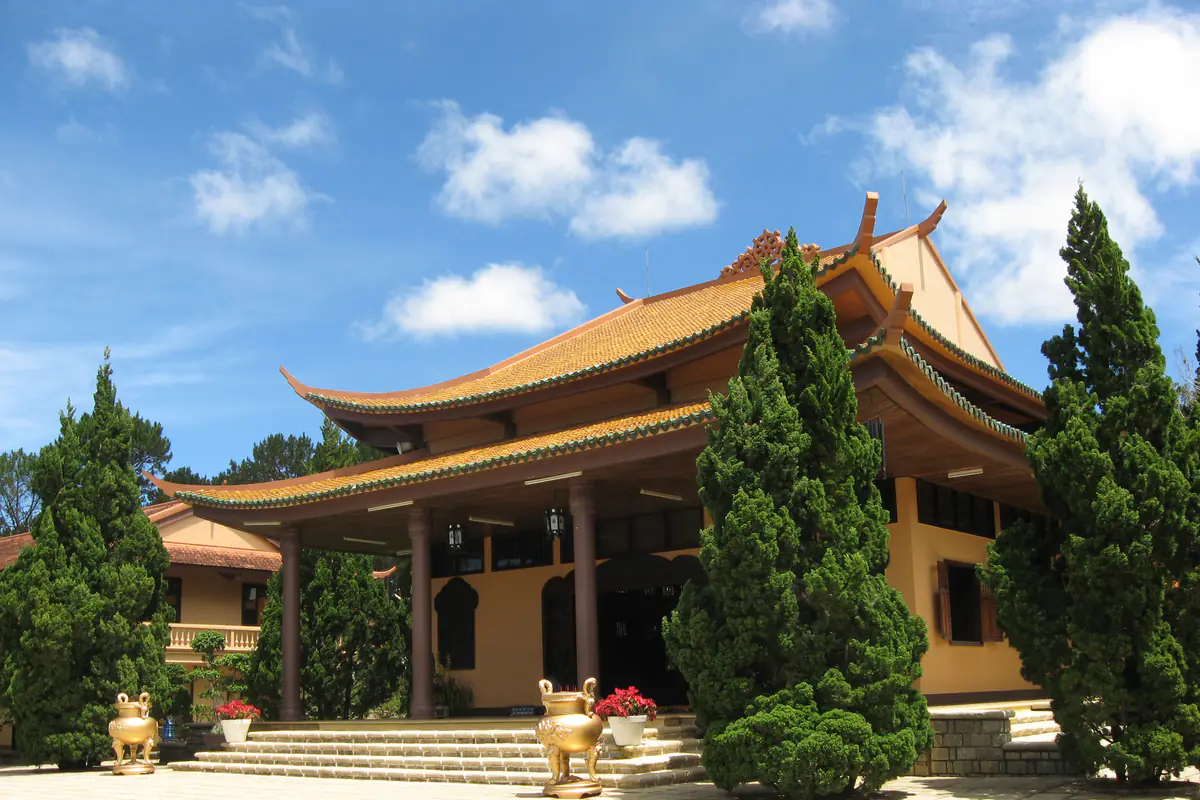 Chánh điện Thiền viện Trúc Lâm Đà Lạt với mái cong lợp ngói nâu, hàng cây tùng hai bên và lư hương trước bậc thềm