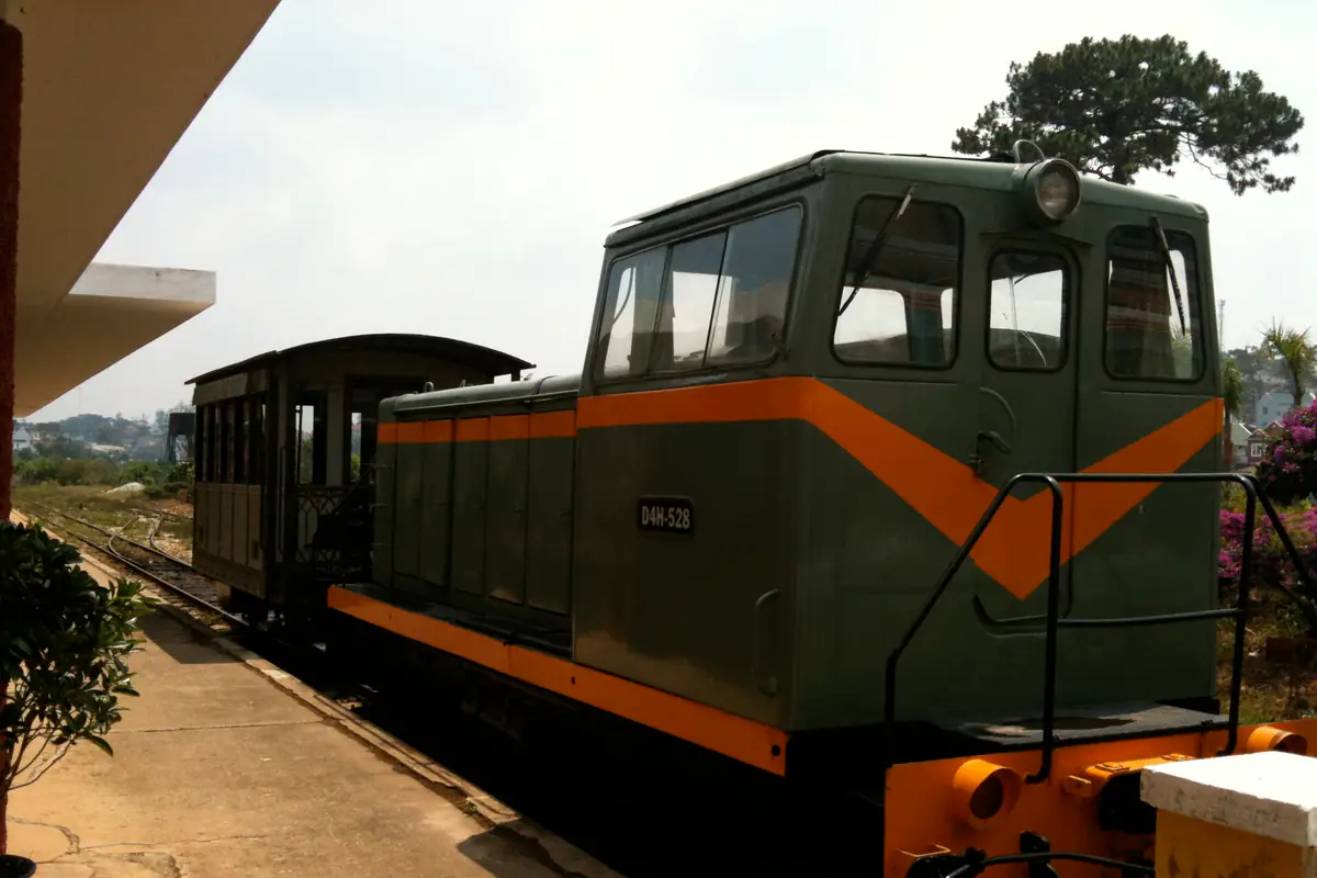 Đầu máy diesel D4H màu xanh sọc cam kéo toa tàu cổ trên đường ray ga Đà Lạt