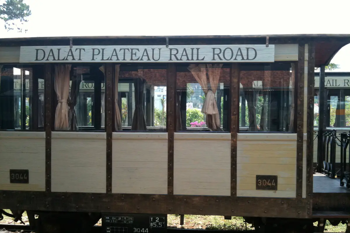 Toa tàu gỗ sơn trắng nâu mang bảng Dalat Plateau Rail Road đậu tại ga Đà Lạt