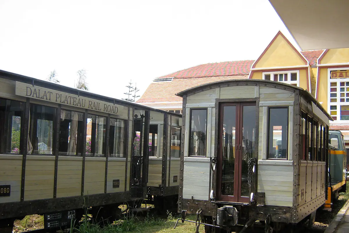 Hai toa tàu gỗ vừa tân trang đậu trên đường ray phía đông ga Đà Lạt, sau lưng là mái chóp vàng
