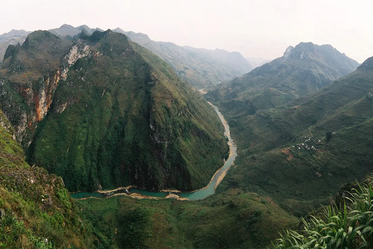Sông Nho Quế màu xanh ngọc uốn quanh chân một khối núi đá dựng đứng, nhìn từ đèo Mã Pí Lèng, ảnh chụp phim