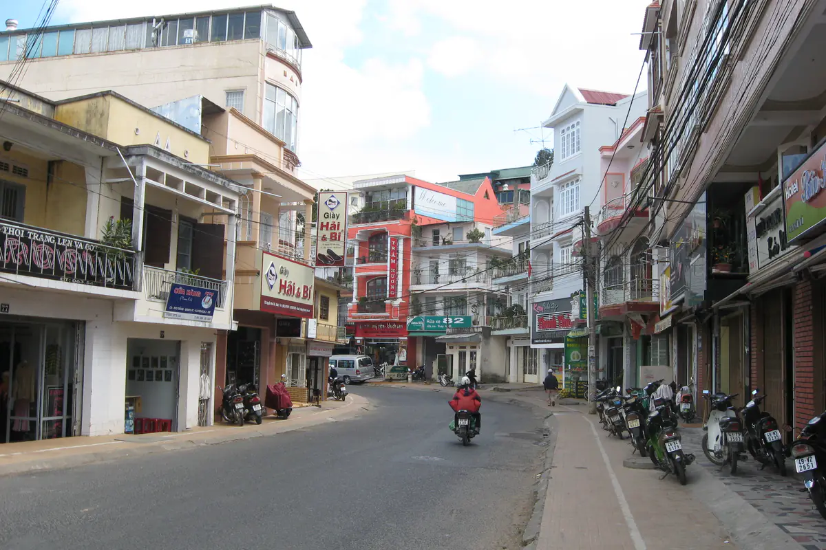 Một đoạn đường Nguyễn Văn Trỗi ở trung tâm Đà Lạt, hai bên là nhà phố và xe máy đỗ trên vỉa hè