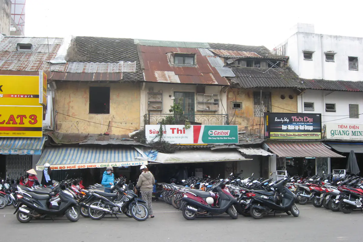 Rows of motorbikes parked along the sidewalk in front of old shophouses in the Hoa Binh area of central Da Lat