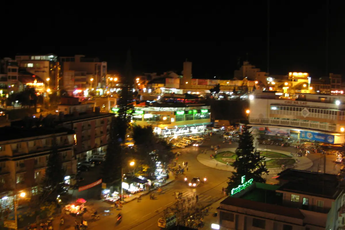 Da Lat Market and the central roundabout at night seen from above, with lit-up hotels and shophouses around the market