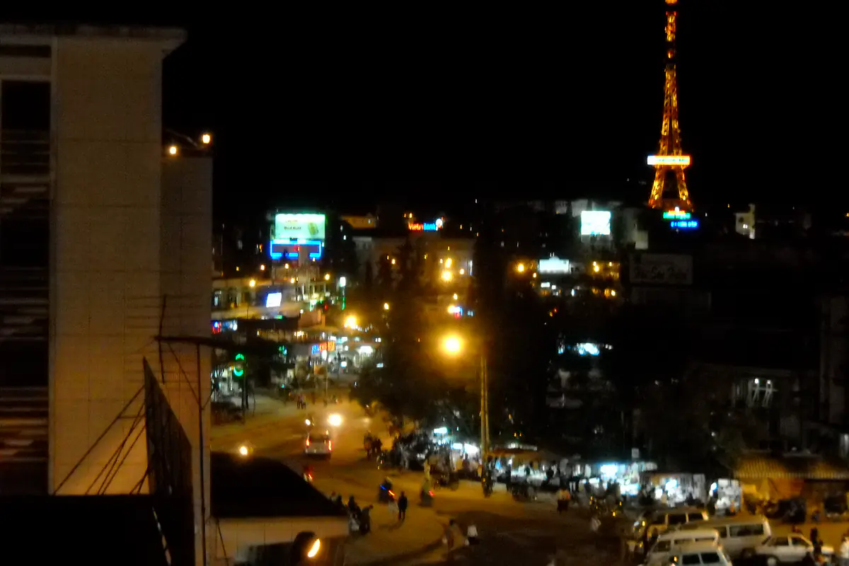 Central Da Lat streets at night seen from an upper floor, with the lit-up Da Lat Post Office tower in the distance