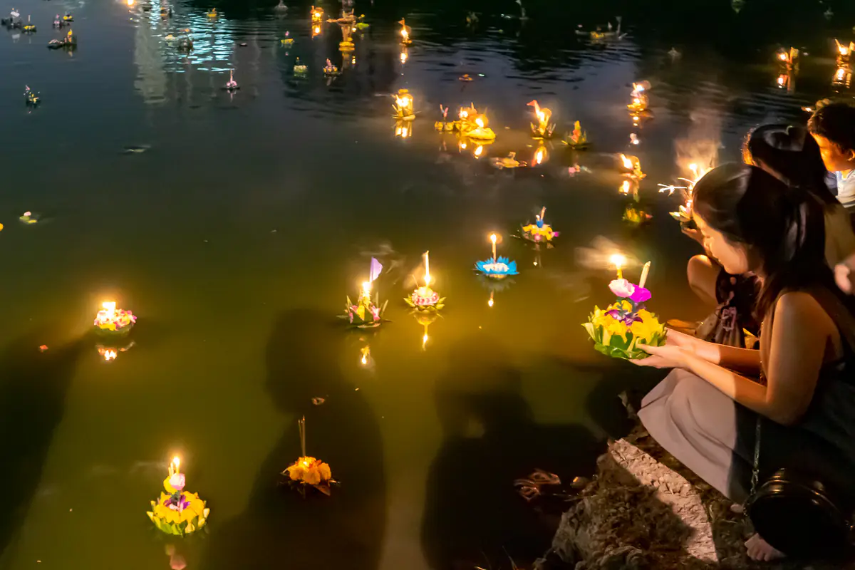 Một cô gái ngồi bên bờ hồ thả krathong thắp nến giữa nhiều krathong khác trong đêm Loy Krathong ở Bangkok, tháng 11/2017