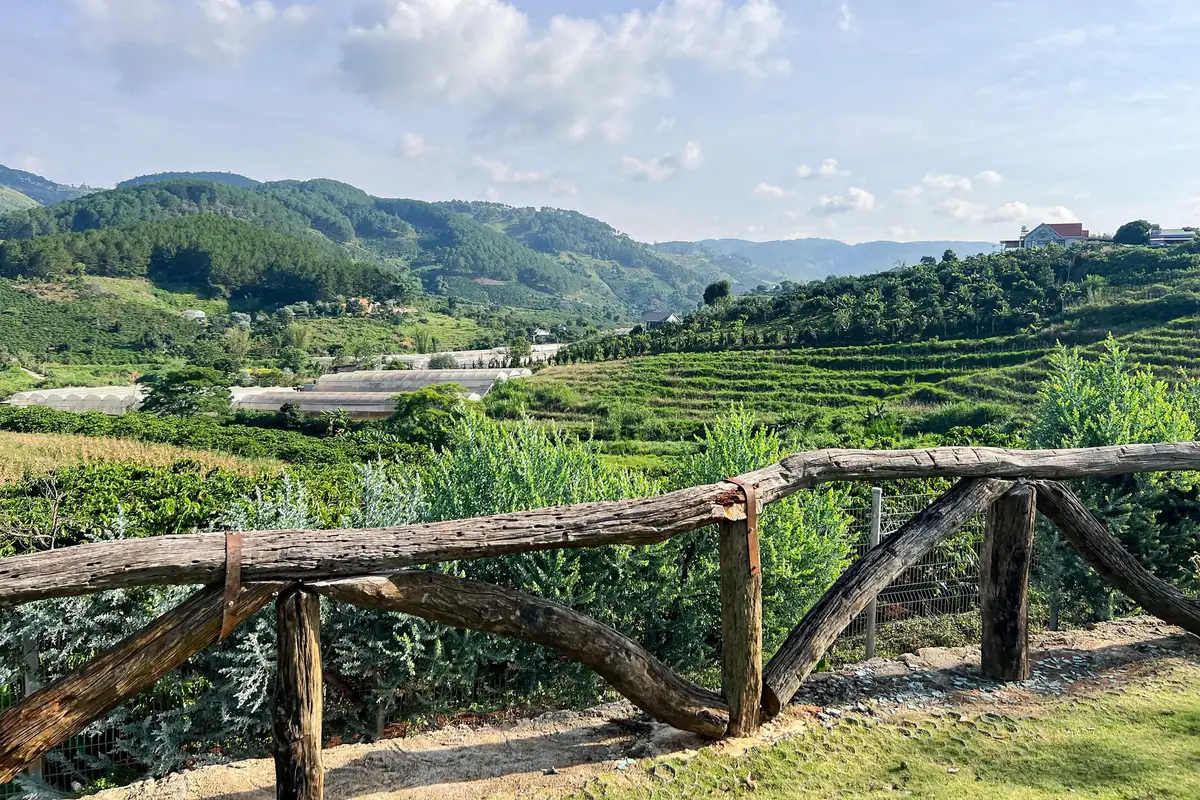 The valley, farm slopes and greenhouses seen from a wooden railing