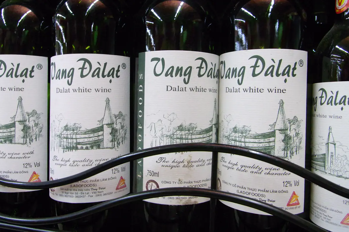 Hàng chai Vang Đà Lạt trắng trên kệ, nhãn ghi 12% Vol, 750 ml và tên Công ty cổ phần Thực phẩm Lâm Đồng