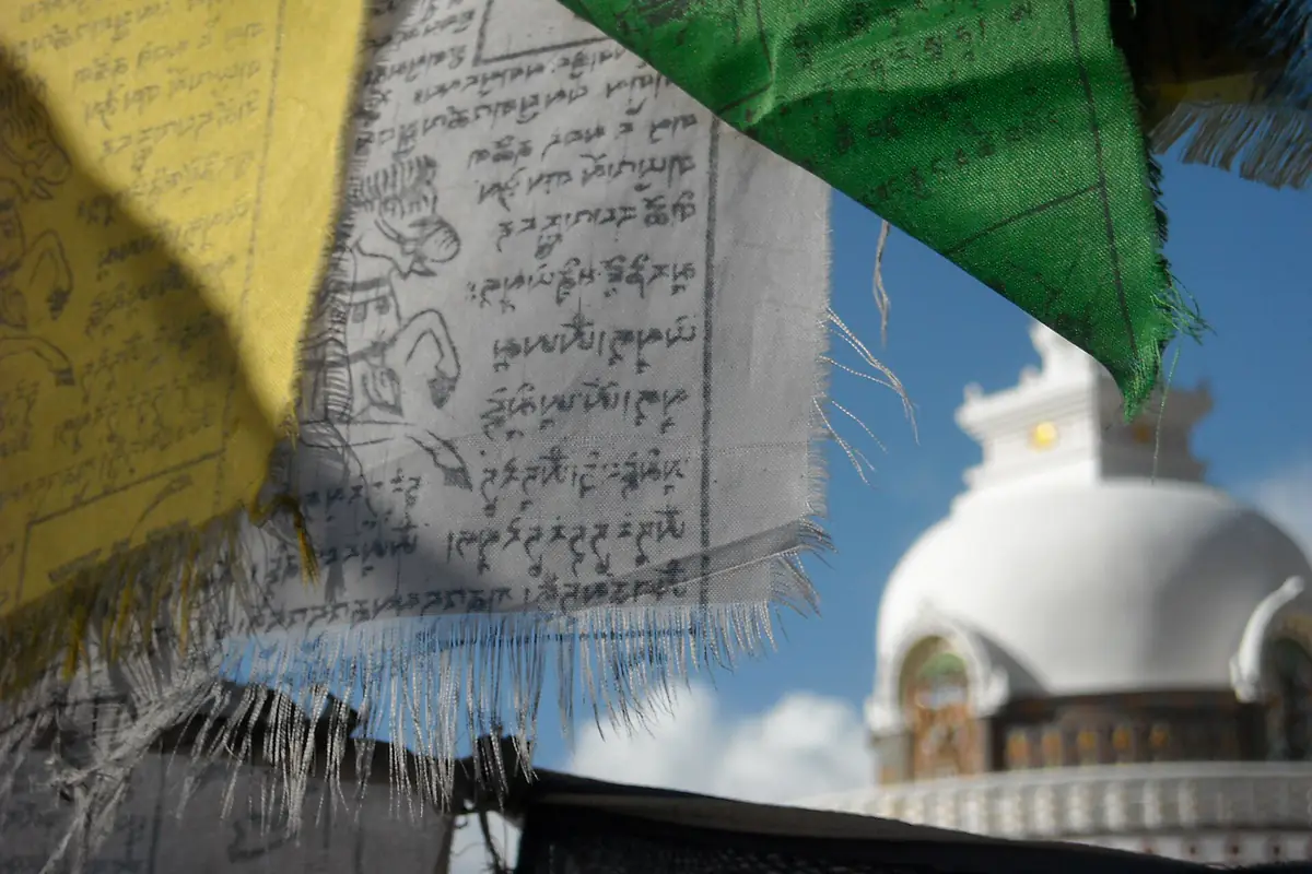 Cờ lungta in kinh văn Tây Tạng bay trước bảo tháp trắng Shanti ở Leh, Ladakh, ảnh minh họa không gian Phật giáo Kim Cương thừa như Samten Hills Đà Lạt