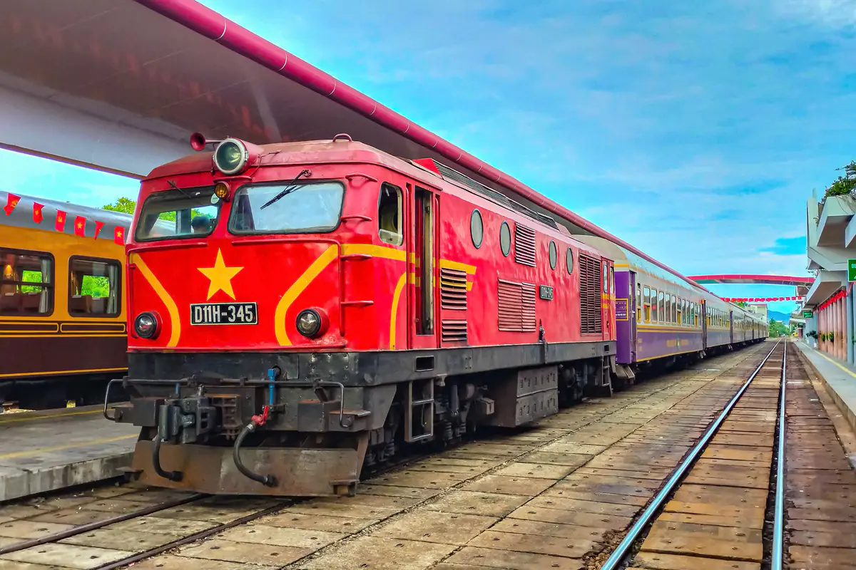 Đầu máy D11H-345 sơn đỏ ngôi sao vàng kéo tàu khách di sản HĐ1 Huế - Đà Nẵng với các toa màu tím, đón khách ở đường số 2 ga Huế sáng 2/9/2026