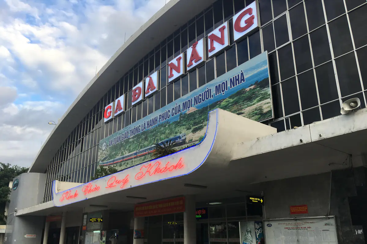 Mặt tiền ga Đà Nẵng với dòng chữ Ga Đà Nẵng màu đỏ trên mặt kính, mái sảnh cong và biển Kính chào quý khách, buổi sáng tháng 7/2018