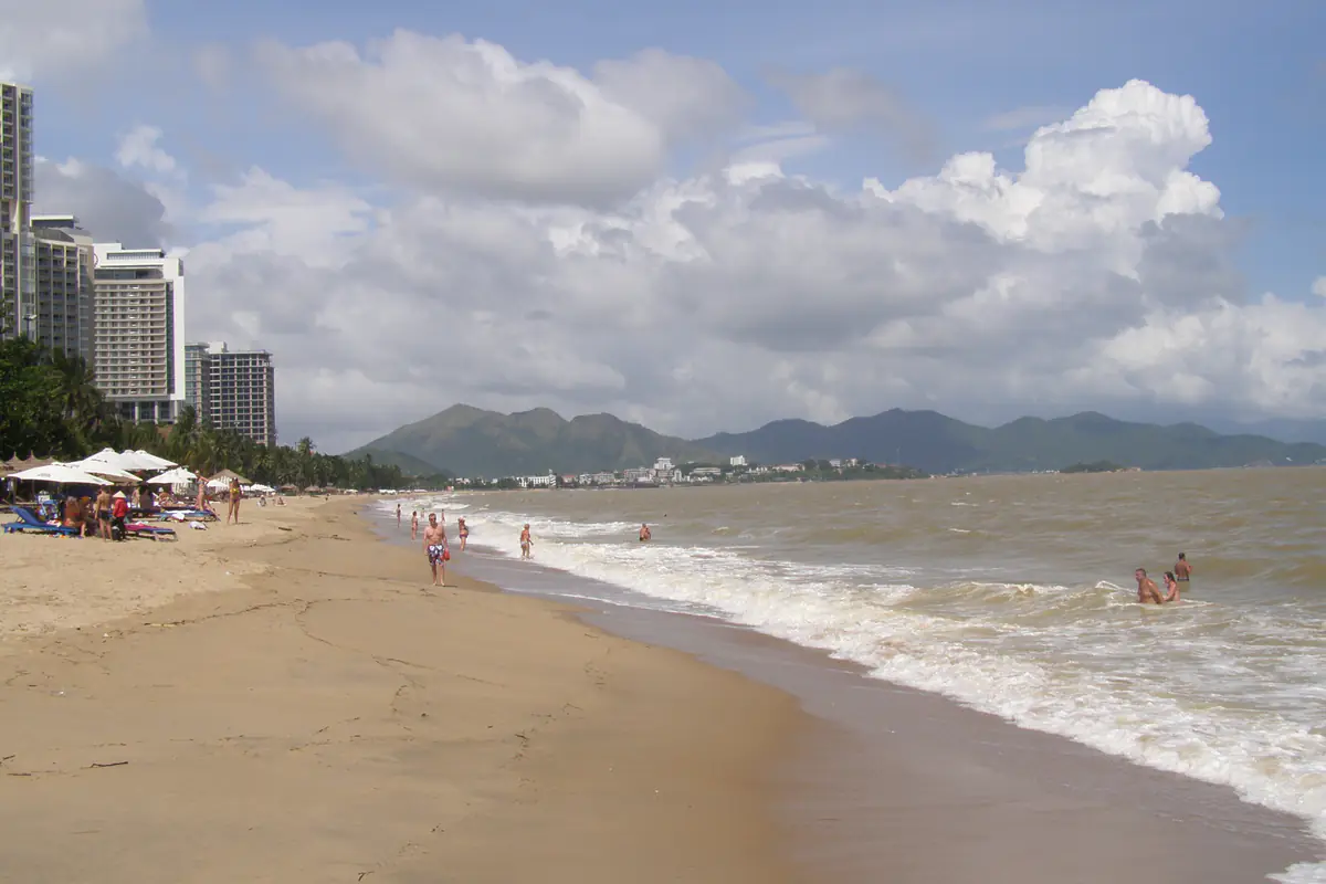 Bãi biển Nha Trang ngày sóng lớn, nước biển đục màu nâu, mây tích dày, dãy khách sạn cao tầng bên trái và dãy núi phía xa, tháng 11/2013