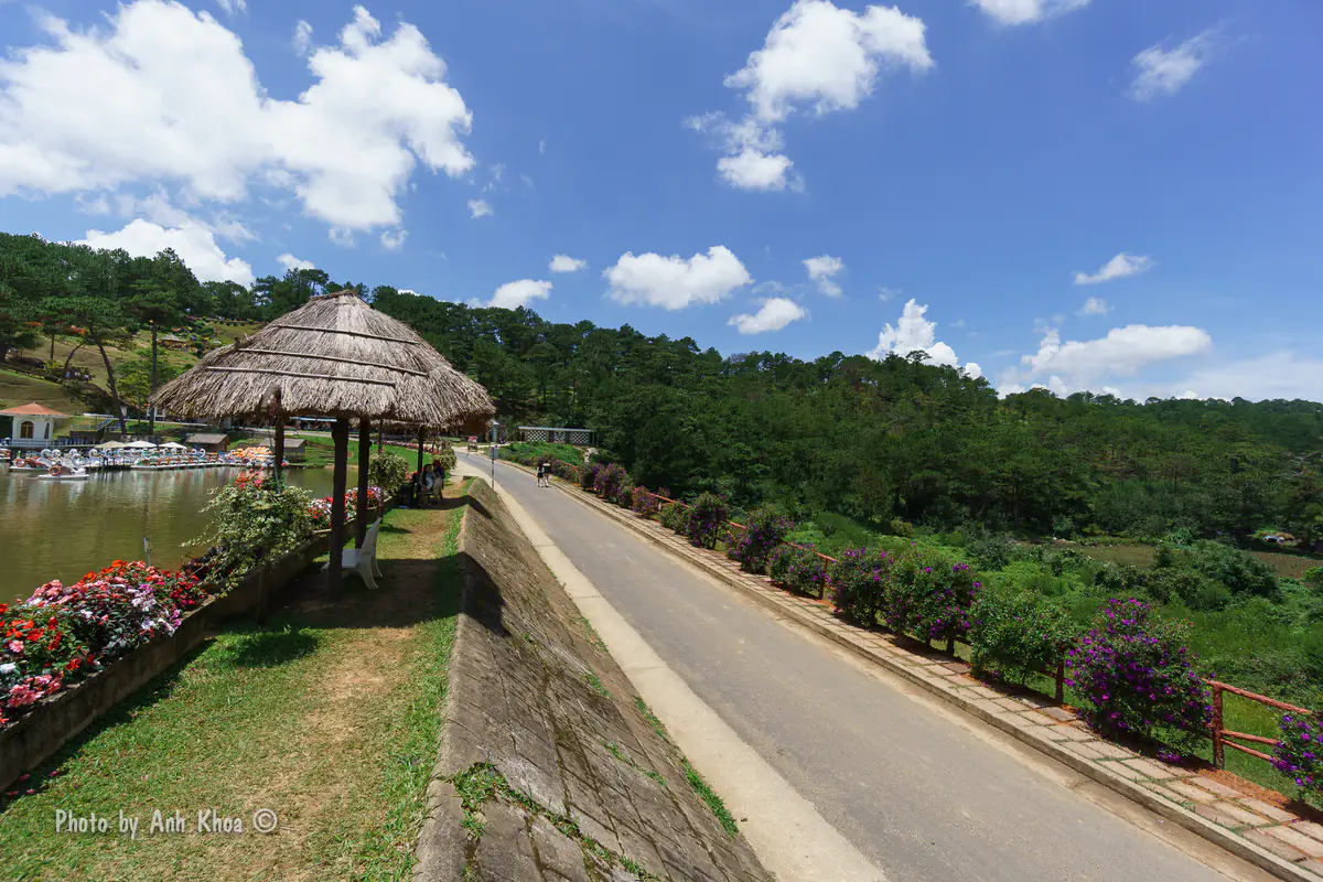 Con đường chạy dọc mặt đập ven hồ Đa Thiện với chòi mái lá và bồn hoa trong Thung lũng Tình Yêu Đà Lạt