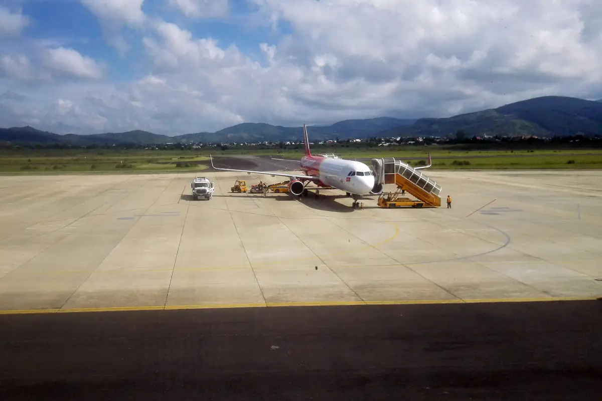 Máy bay Vietjet đỗ trên sân đỗ sân bay Liên Khương, xe thang và xe hành lý bên cạnh, phía sau là đồi núi Lâm Đồng