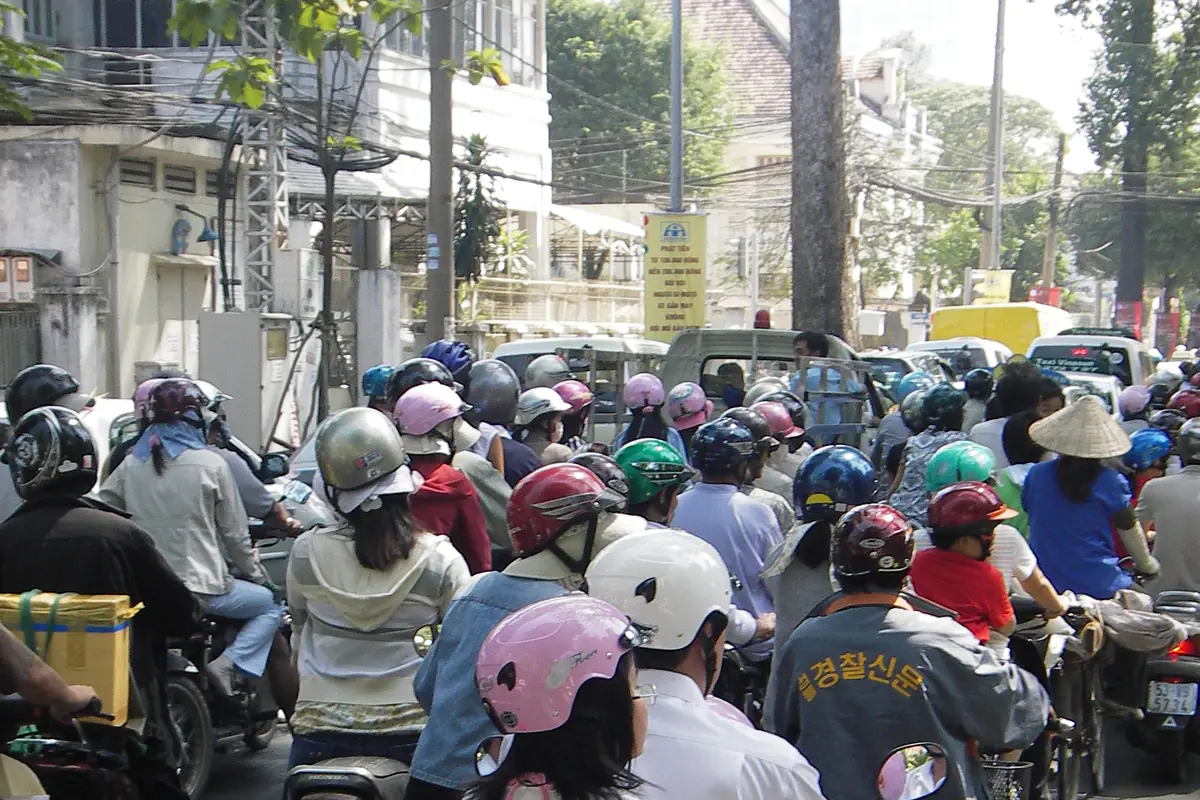 Hàng trăm xe máy đứng sát nhau chờ đi gần Dinh Độc Lập, TP.HCM, người lái và người ngồi sau đều đội mũ bảo hiểm nhiều màu, tháng 12/2007