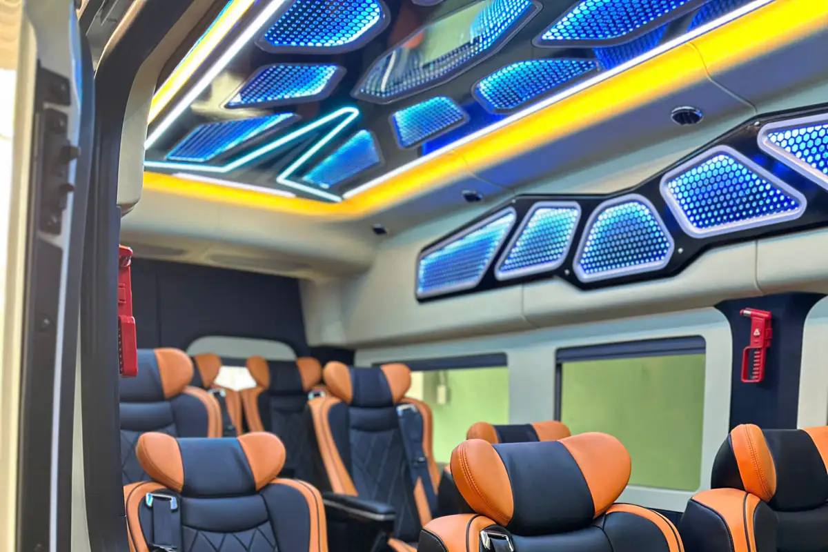 Black reclining seats with orange trim beneath colorful ceiling lights in a Cuc Tung vehicle